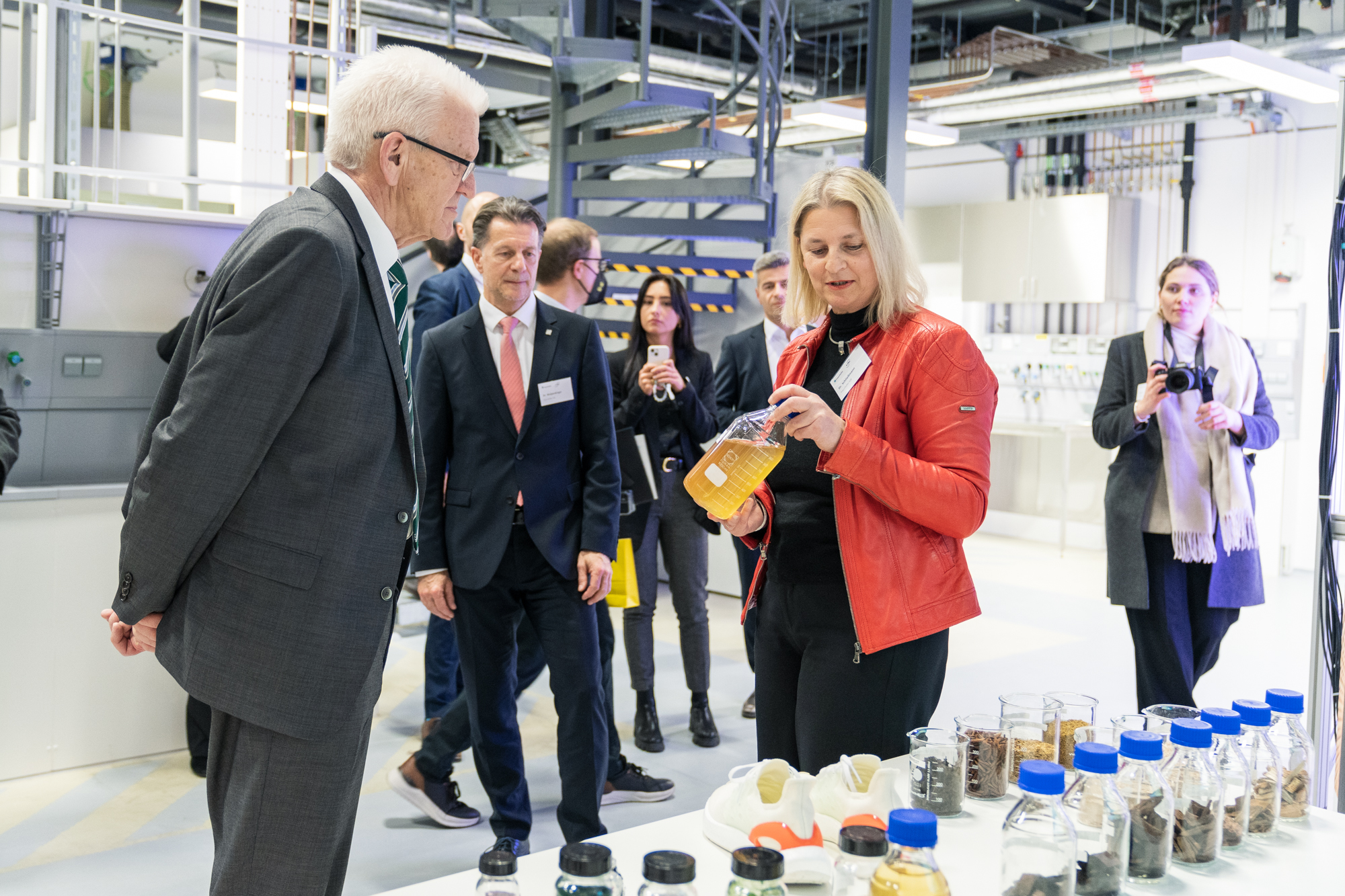 Dr.-Ing. Ursula Schließmann erklärt Bioraffinerien MP Kretschmann besucht S-TEC, Dr. Ursula Schließmann zeigt ein Gefäß mit Abwasser